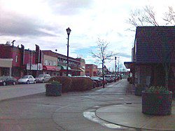 ![A street with parked cars and a cloudy sky.